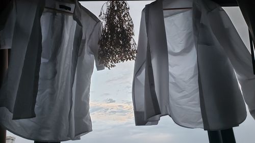 Clothes hanging in row at store against sky