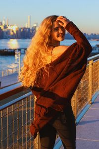 Woman standing by railing against sky