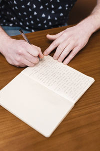 Hands of man writing in notebook sitting at cafe