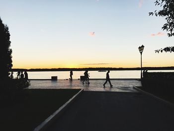 Silhouette people on beach against sky during sunset