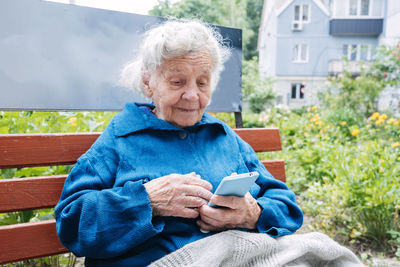 Senior woman using smart phone on bench