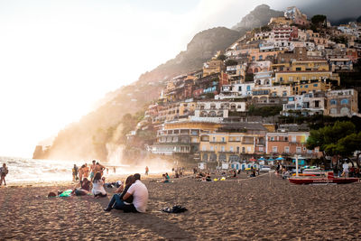 People on beach by city against sky