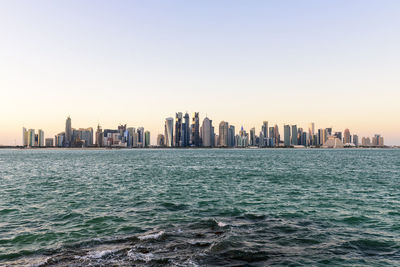 Sea and cityscape against clear sky