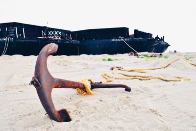 Rusty metal on beach against clear sky