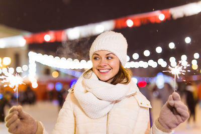 Portrait of smiling young woman standing at night during winter