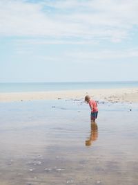 Boy standing on beach against sky