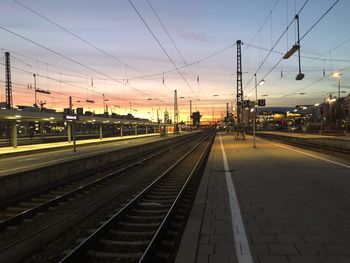 Railroad station platform against sky at sunset