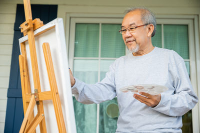 Portrait of senior man using mobile phone while standing at home