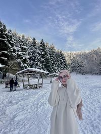 Portrait of smiling woman standing on snow covered landscape