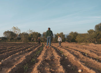 Rear view of men on agricultural field against sky