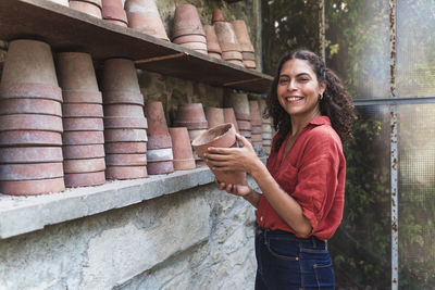 Portrait of smiling young woman standing against wall