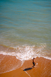 High angle view of mature man walking on beach during sunny day