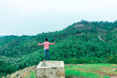 Rear view of man standing by tree against sky