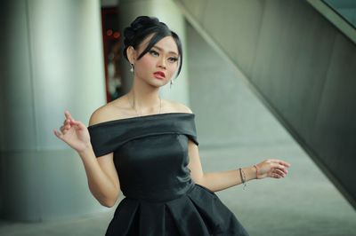 Portrait of young woman standing against wall