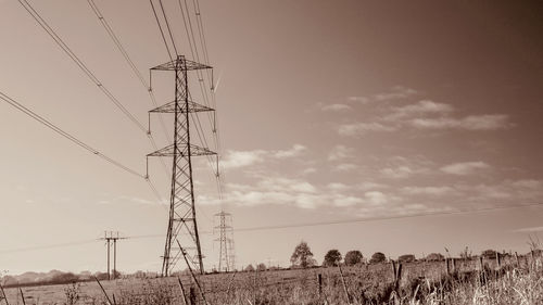 Low angle view of electricity pylon on field against sky