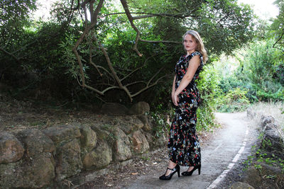 Portrait of woman standing by tree in forest