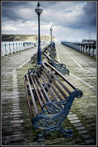 Bicycles on railing by bridge against sky