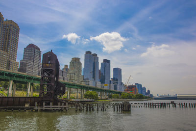Modern buildings by river against sky in city