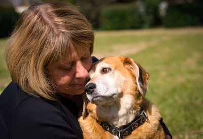 Woman embracing dog on field