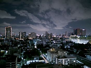 Illuminated cityscape against cloudy sky