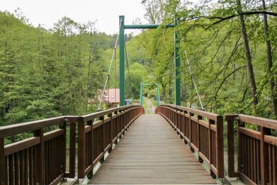 Footbridge over river in forest against sky