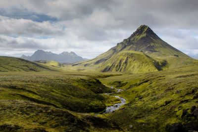 Scenic view of mountain range against cloudy sky