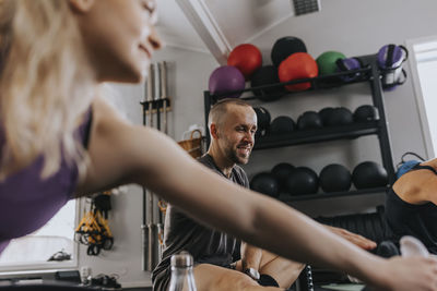 Smiling man sitting on floor and looking away during fitness class