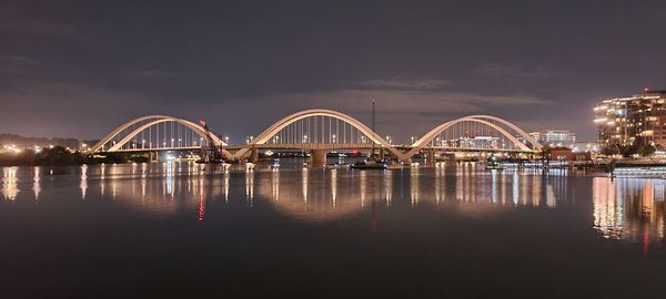 Illuminated bridge over river at night