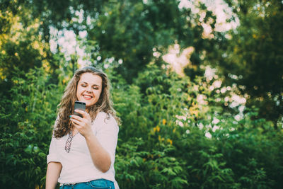 Young woman standing against plants