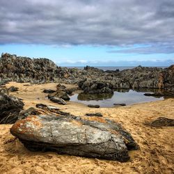 Rock formations on shore against sky
