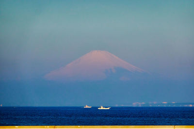 Scenic view of sea with snowcapped mountain against sky