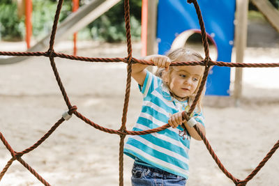 Cute girl climbing on jungle gym in playground