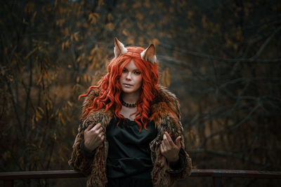 Young woman standing against tree during autumn