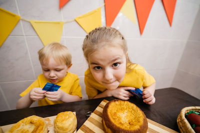 Children boy and girl prepare festive sweets decorate easter colored eggs on the table