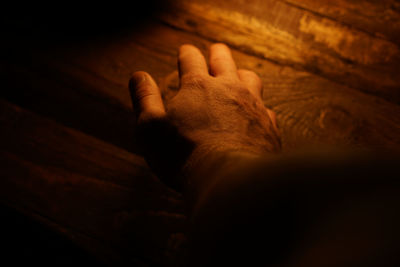 Cropped hand of man touching wooden table