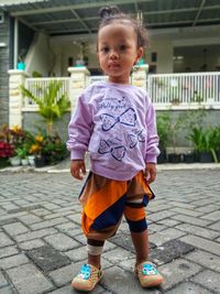 Portrait of cute girl standing on footpath