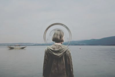 Rear view of woman standing in sea against sky