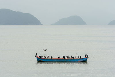 People on boat in sea against sky