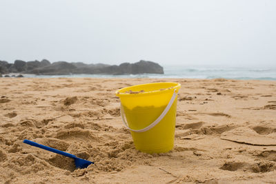 Close-up of yellow umbrella on beach against clear sky