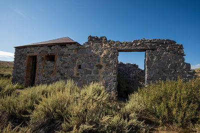 Old stone building ruins in ghost town against clear blue sky