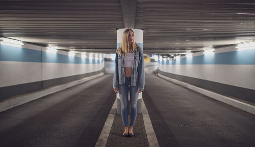 Woman standing under illuminated tunnel