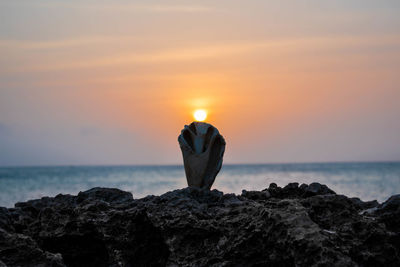 Scenic view of rocks in sea against sky during sunset