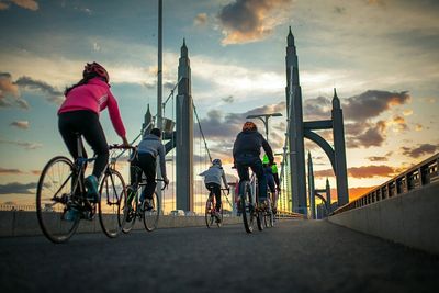 People riding bicycle on road against sky