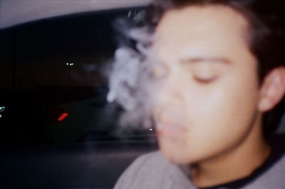 Close-up portrait of young man smoking in car