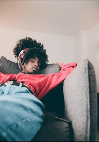 Portrait of boy sitting against wall at home