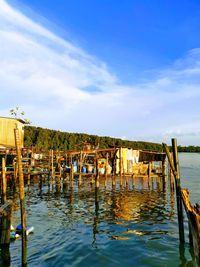 Wooden posts in sea against sky