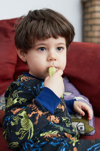Portrait of boy looking away while sitting on sofa at home