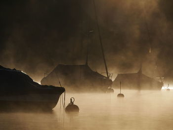 Silhouette sailboats in sea against sky at night