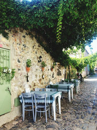 Empty chairs and tables against wall in city