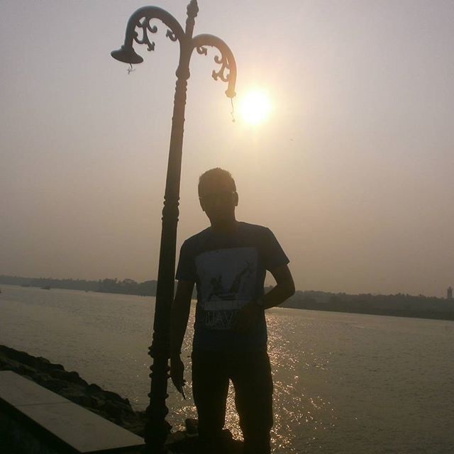 water, standing, lifestyles, silhouette, leisure activity, sunset, sun, three quarter length, men, rear view, sea, sky, full length, reflection, clear sky, tranquility, casual clothing, holding